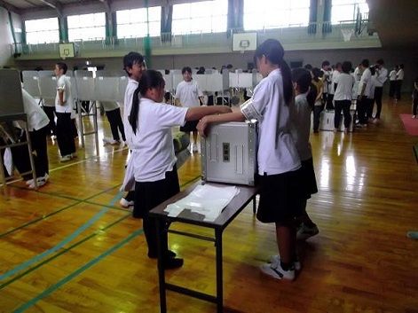 西中学校体育館で投票箱に投票する生徒の写真